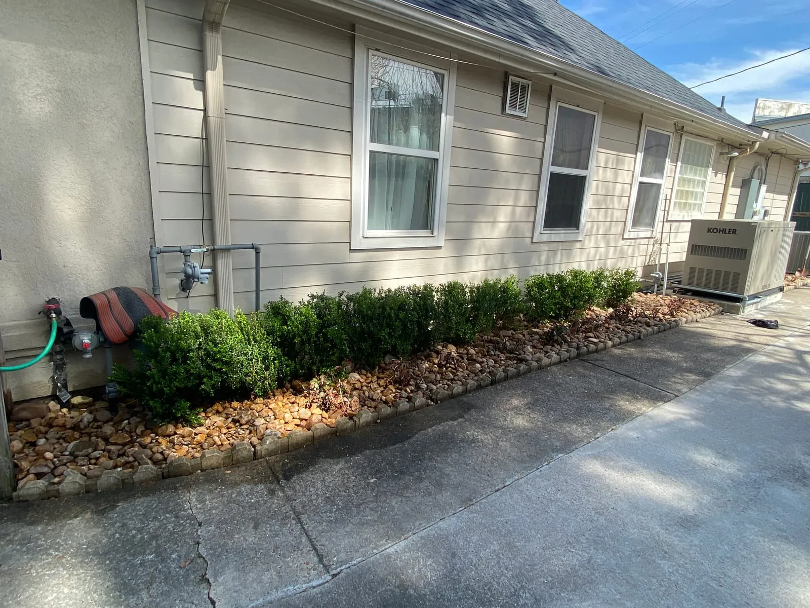Real Stoneway rock bed with block edging alongside a house